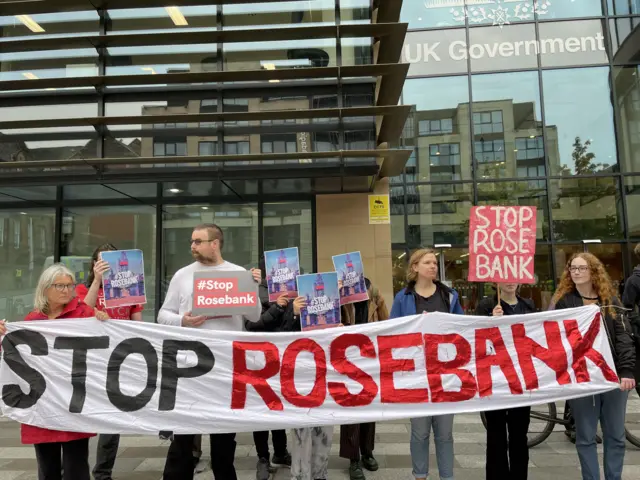 Protesters holding anti-Rosebank signs