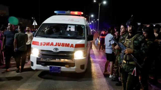 Security forces keep watch next to an ambulance near a hospital following a fatal fire at a wedding celebration, in Iraq's Nineveh provinc