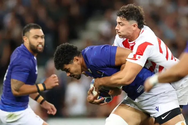 Samoa's lock Theo McFarland is tackled by Japan's centre Dylan Riley