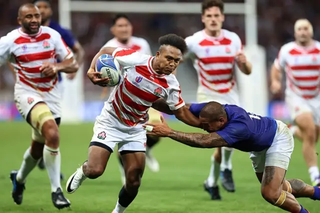 Japan's right wing Kotaro Matsushima hands off a tackle from Samoa's right wing Ed Fidow