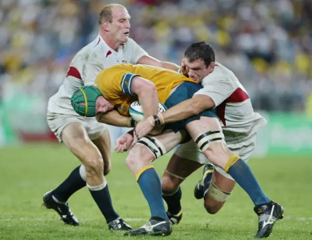 Wallaby David Lyons is takled by English captain and lock Martin Johnson and English Lawrence Dallaglio