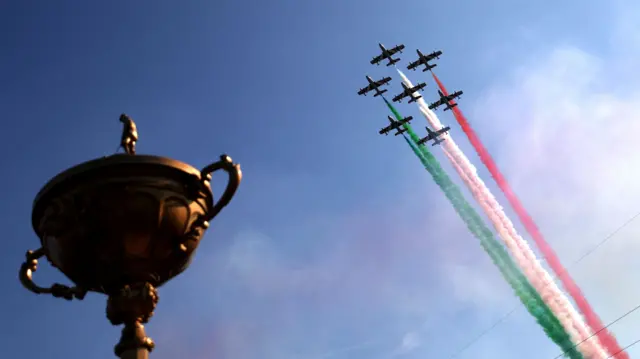 The Ryder Cup with planes in the background displaying colours of the Italian flag