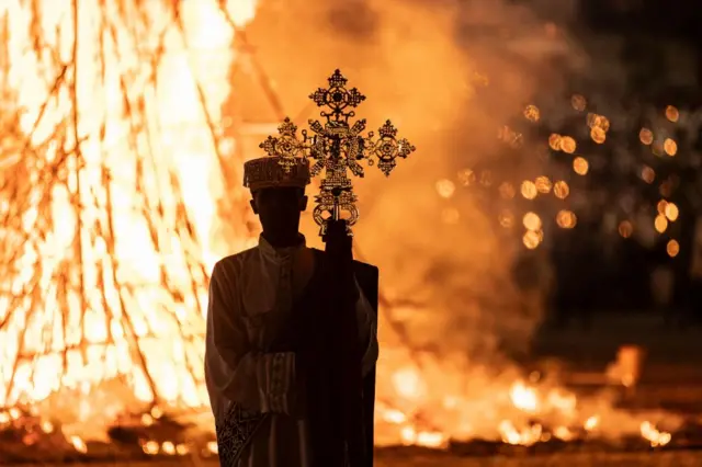 A high priest holds a cross while standing in front of a bonfire during the celebrations of the Ethiopian Orthodox holiday of Meskel in Addis Ababa on September 27, 2023.