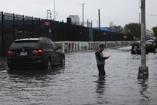 A man and a car stand in rising flood water in Red Hook, Brooklyn