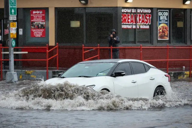 A car drives along a flooded street in the Brooklyn borough of New York City