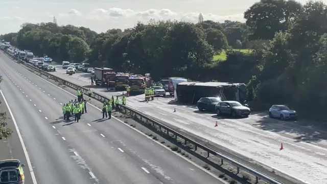 coach lying on its side surround by emergency vehicles.