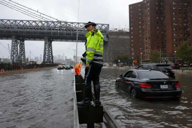 A police officer from the NYPD Highway Patrol looks on near cars stuck in a flooded motorway at the FDR Drive in Manhattan near the Williamsburg bridge, in New York City