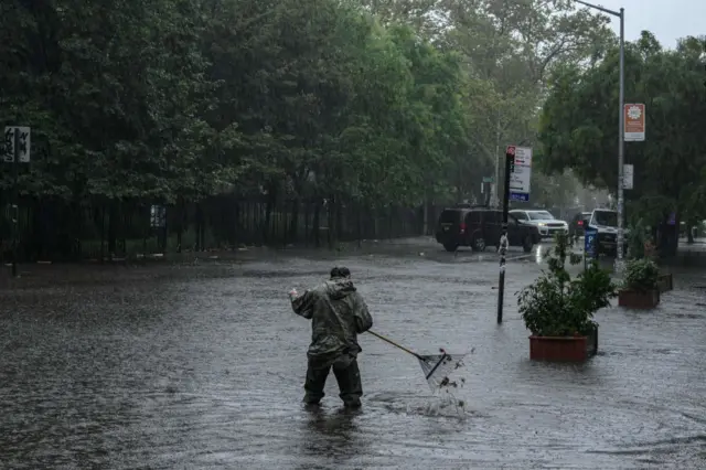 A man clears debris from a drain in floodwater in Brooklyn on September 29