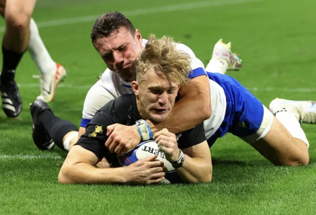 New Zealand's Damian McKenzie scores their eleventh try as an Italian player attempts to tackle him