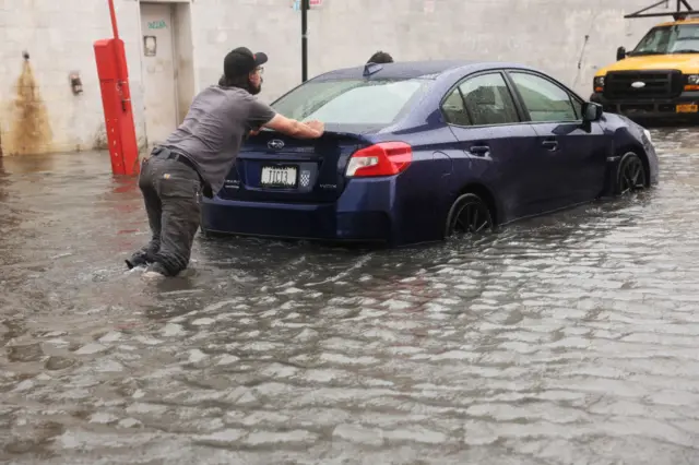 A man pushes a car through the Red Hook neighbourhood of Brooklyn