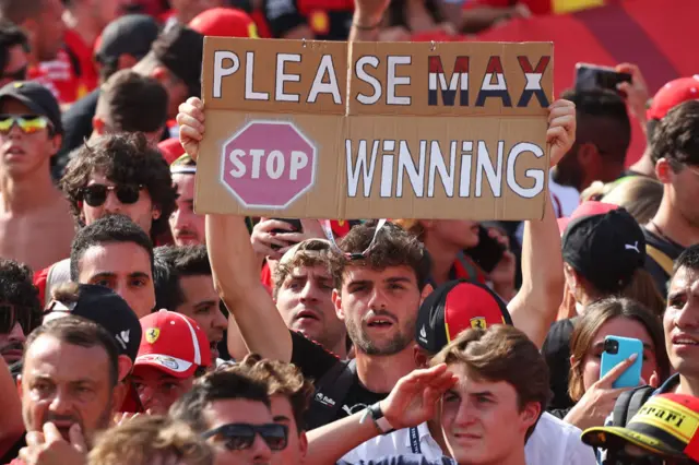 A fan holds a sign hoping Max Verstappen stops winning