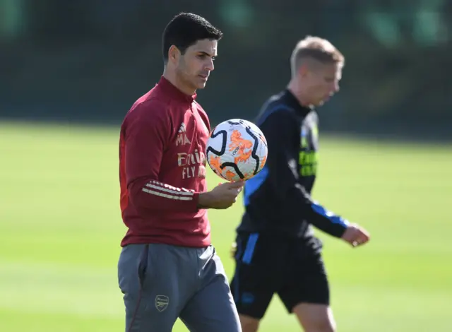 Arteta carries the ball to a designated spot in training.