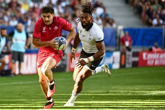 Georgia's wing Davit Niniashvili runs with the ball as Fiji's centre Waisea Nayacalevu