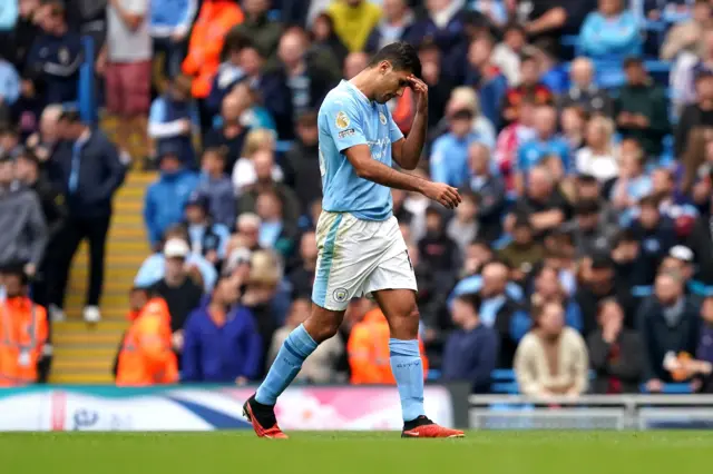 Rodri mops his brow while exiting the pitch after a red card.