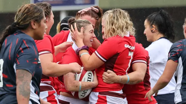 Wales players celebrate with try scorer Keira Bevan