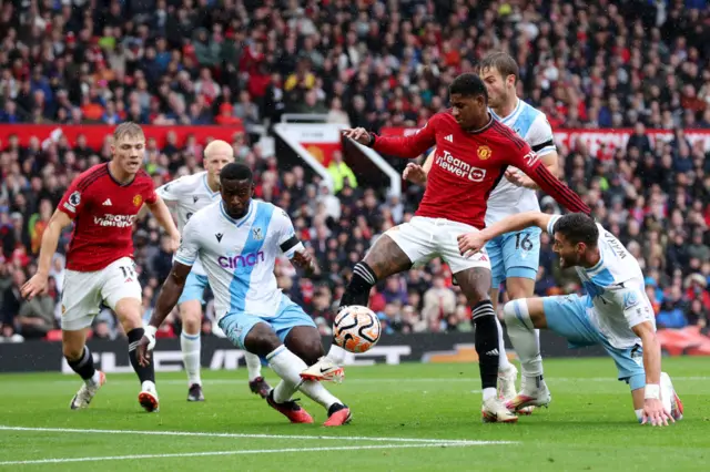 Marcus Rashford on the ball whilst under pressure from Marc Guehi and Joel Ward