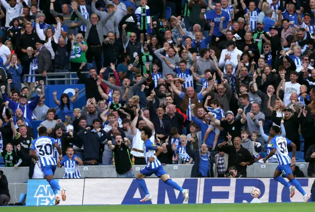 Mitoma celebrates scoring for Brighton while being pursued by teammates.