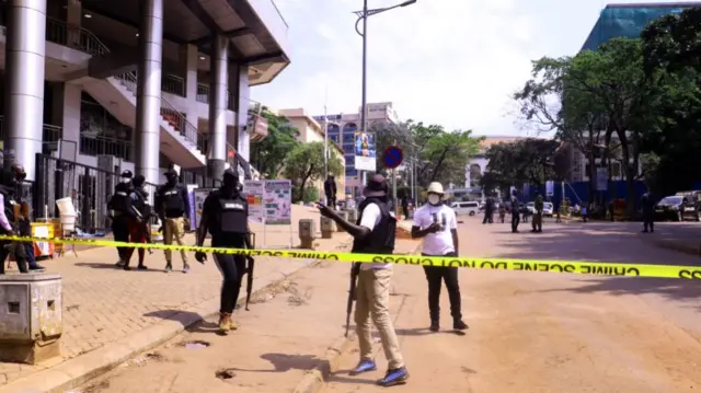 Police officers inspect around sites after two blasts occurred with one just meters away from the main gate to the country's parliament and the other near the city's central police station, in Kampala, Uganda on November 16, 2021.