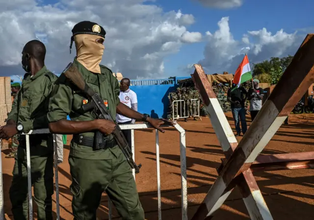 Niger's security officers stand guard as supporters of Niger's National Council of Safeguard of the Homeland (CNSP) gather oustide Niger and French airbase in Niamey on September 3, 2023, to demand the departure of the French army from Niger.