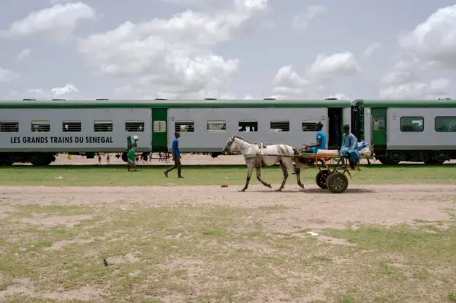 A horse-drawn carriage passes along the train in Bambey, on the way to Touba, Senegal - September 2023