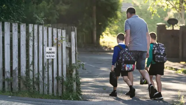 A man walks two young boys to school