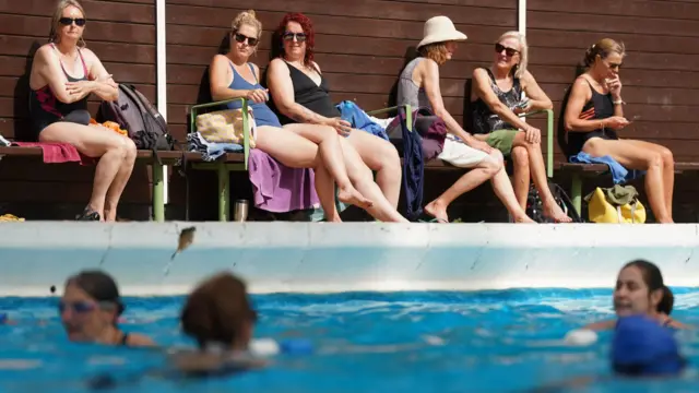 People sat by a swimming pool