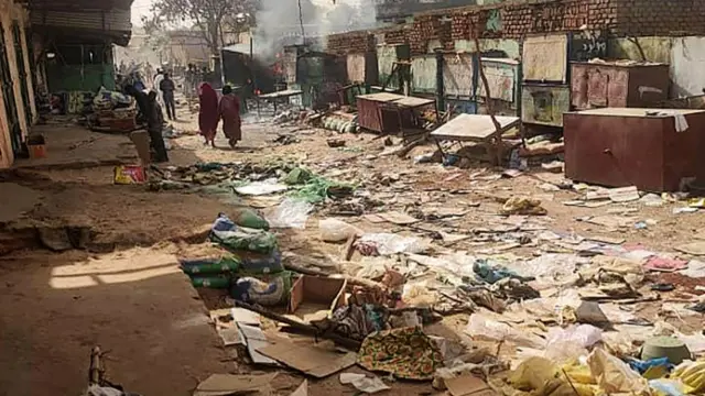 People walk among scattered objects in the market of El Geneina, the capital of West Darfur