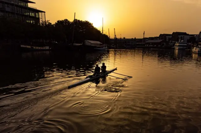 Rowers make ripples across Bristol Harbourside as the sun rises over the city and forecasters predict a "last dose of summer", with warm spells reaching 30C on Tuesday in southern areas of England, and 32C on Wednesday and Thursday in central and southern England.