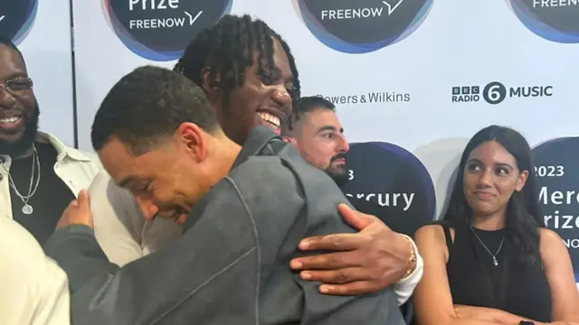 Loyle Carner hugging Ife Ogunjobi, Ezra Collective