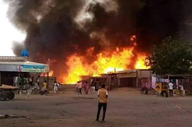 A man stands by as a fire rages in a livestock market area in al-Fasher, the capital of Sudan's North Darfur state, on September 1, 2023,