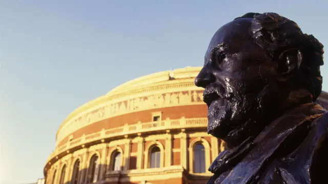 A statue of Henry Wood pictured close up from outside Royal Albert Hall, with the building visible in the background