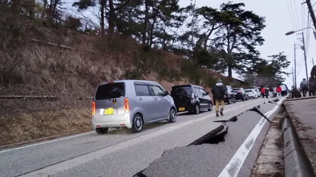 People walk along a road damaged by an earthquake, in Wajima, Ishikawa prefecture,