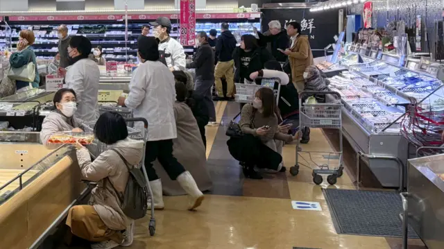 Shoppers crouch down in a supermarket