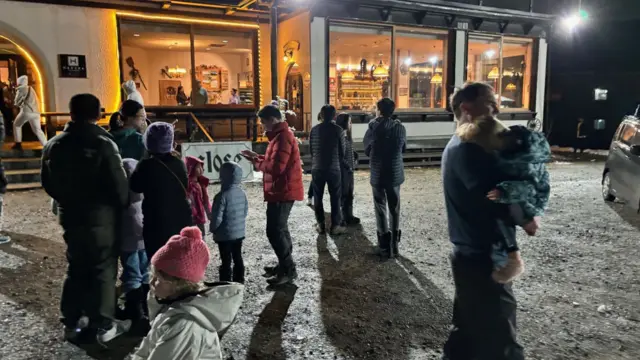 A group of people stand outside a building in the darkness