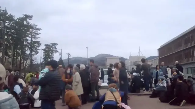 People evacuate to higher ground at a parking space of a junior high school after a tsunami warning issued caused by an earthquak