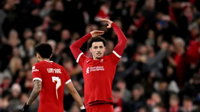 Curtis Jones waves at the Anfield crowd to encourage more noise after scoring a goal.