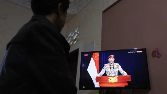 A person watches a television during a broadcast by Houthi spokesman Yahya Saree