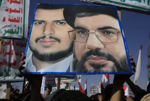 A person holds up a poster depicting the leader of Hezbollah and the Houthi leader during a protest in Yemen