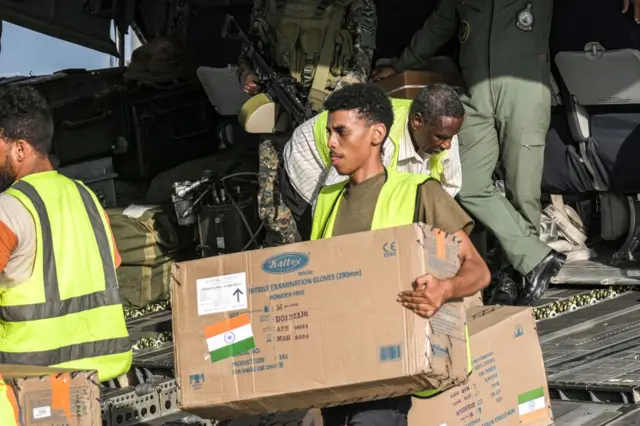 Humanitarian aid packages provided by India to Sudan are unloaded off of an Indian Air Force military transport aircraft on the tarmac at Port Sudan airport on May 18, 2023.