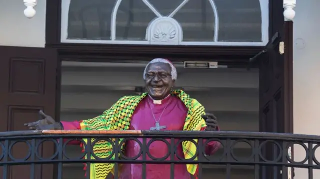 A life-size statue of the late Archbishop Desmond Tutu with a Palestinian scarf is seen standing on the balcony of the Desmond and Leah Tutu foundation.