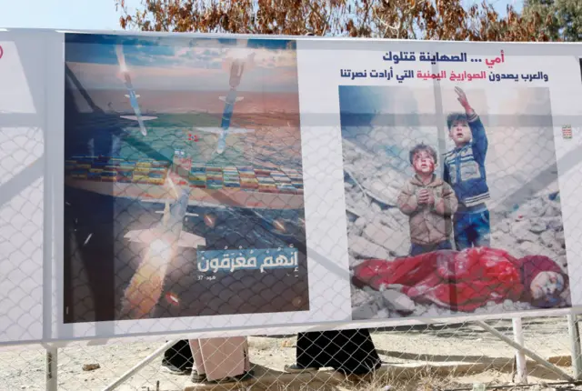 A protester in Yemen on Wednesday holds a poster showing missiles targeting cargo ships