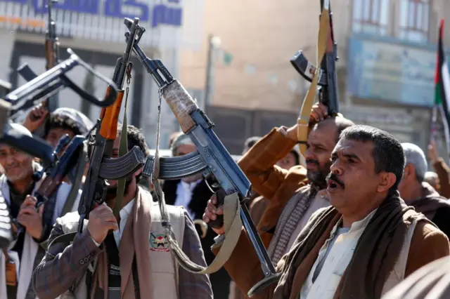 Newly-recruited members of the Houthis' popular army hold up their weapons during a gathering at the end of a military training