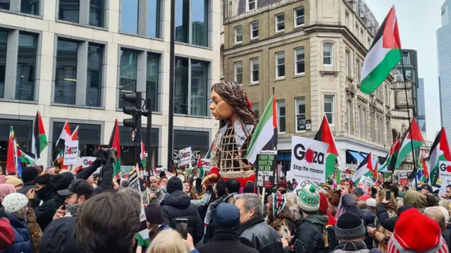 Protesters in London with the "Little Amal" model