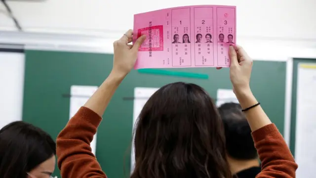 An election worker in new Taipei City holds up a ballot for verification