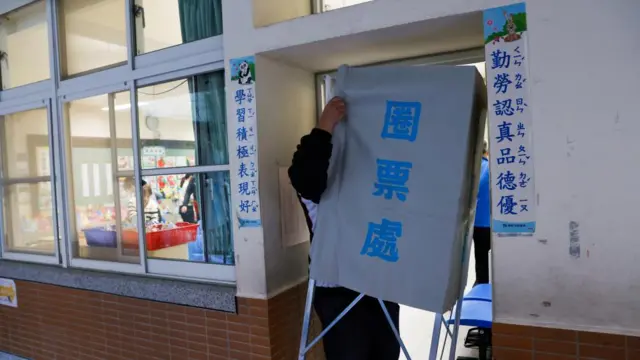 An election worker carries a voting booth in New Taipei City