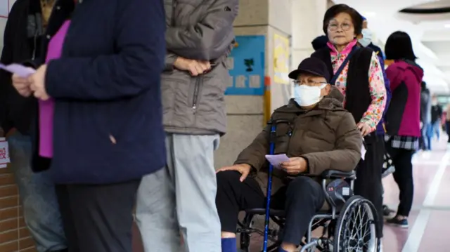 People wait in line to vote in the presidential elections at a polling station in a elementary school in New Taipei City