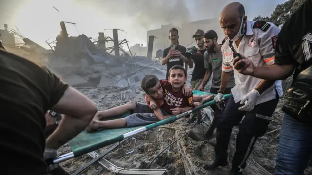 Palestinians carry wounded brothers on a stretcher after recovering them from the rubble in Gaza City