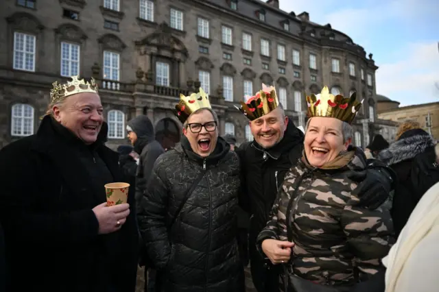 A group sporting card crowns wait outside the palace