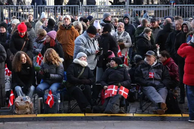 A group of well-wishers hold Danish flags in the palace square