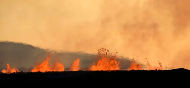 A picture taken today on a road linking Reykjavik and Grindavik shows spraying lava and smoke billowing over the landscape